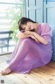 A woman in a purple dress sitting on a wooden floor.