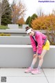 A woman in a pink jacket and yellow shorts posing for a picture.