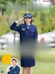 A woman in a military uniform salutes as she stands in front of an airplane.