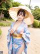 A woman in a blue kimono holding an umbrella.