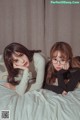 A couple of young women laying on top of a bed.