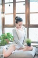 A woman sitting on a couch with a potted plant.