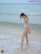 A woman in a white bathing suit standing in the ocean.